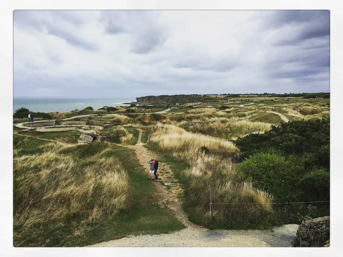 Bomb craters and bunker ruins on the clifftop at Pointe du Hoc, reached only by car or on Normandy tours from Paris